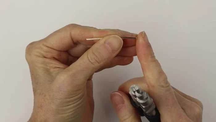 Use the larger part of the bail making pliers to form the hook shape, ensuring both hooks are the same size. File down the sharp ends.