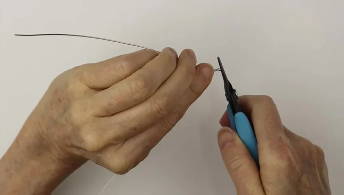 Twist one end around to close it, clip it flush, and pinch the pointy end. Then, twist this end around a ring cone to create a spiral.