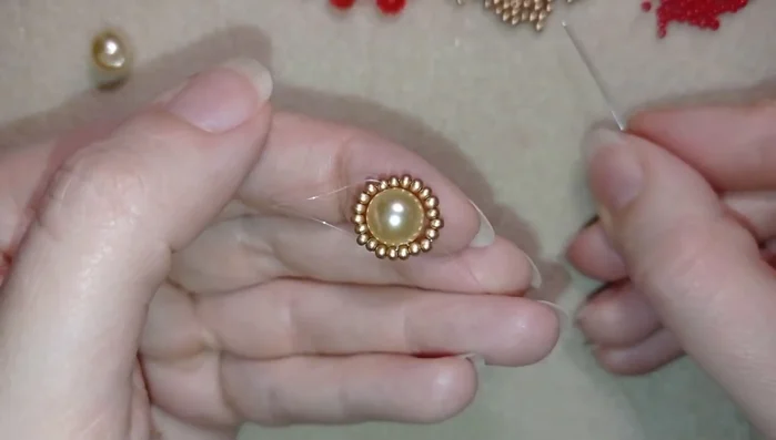 Create petal shapes using the pattern: 2 seed beads, 1 crystal, 2 seed beads. Repeat this pattern 7 times around the pearl, securing each petal by going back through the previous bead.