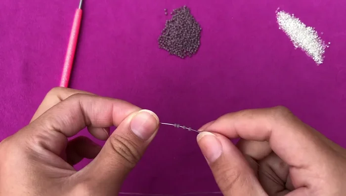 Start the focal unit: String 4 size 11/0 seed beads onto the thread, leaving a tail for knotting later. Create 2 overhand knots.