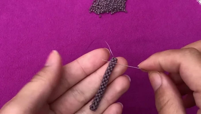 Add the pearl: Attach the pearl between parallel beads within the crocheted unit.