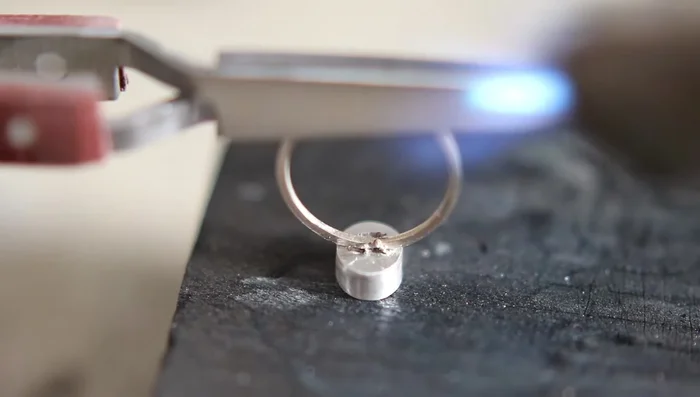 Solder the bezel to the ring band using hard solder paste. Heat tweezers first to avoid heat sink.