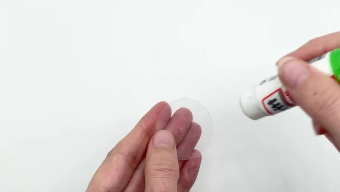 Apply glue stick to one side of the plastic circle and adhere it to the back felt (with the pin already attached).