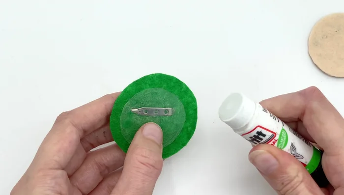 Apply glue stick to the other side of the plastic circle. Attach the front of your design to the plastic, pressing firmly.