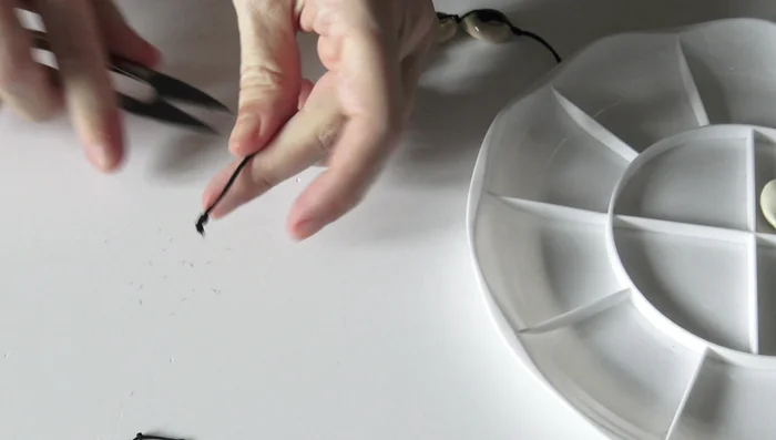 Finish the ends: Trim and burn the ends of the cords to secure the knots.