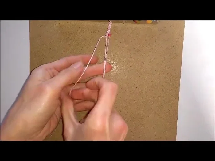 Make one hitch knot over both cords to hold the bead in place.