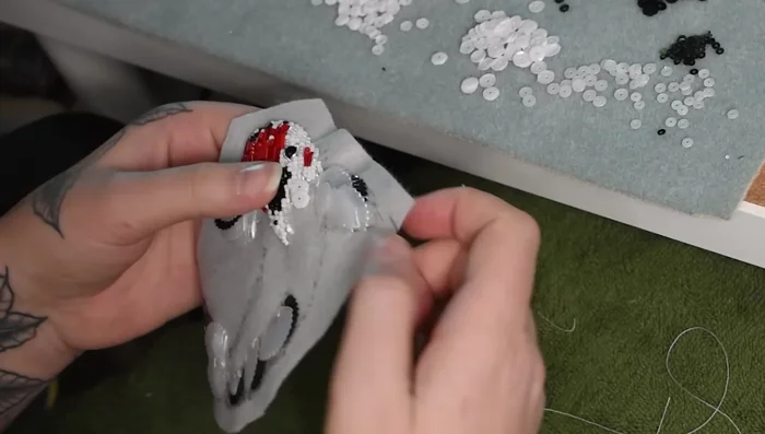 Fill the remaining body with sequins in rows, using cupped sequins to create a fish-scale effect and varying colors for added dimension. Layer smaller sequins over beads where necessary.