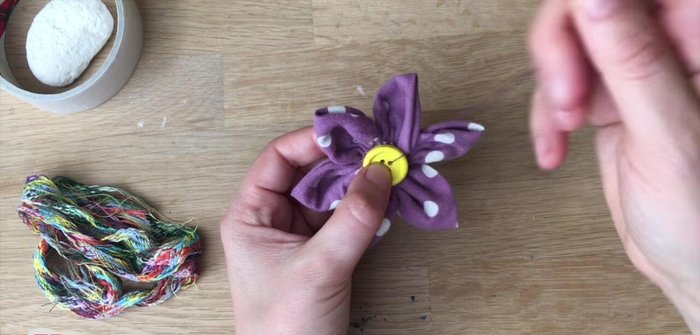 Sew a button to the center of the flower to cover the back stitches.