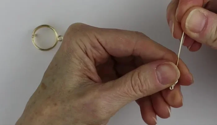 Attach the bead or charm to the loop, securing it by wrapping the wire around the ring's loop and flattening the ends with flat pliers.