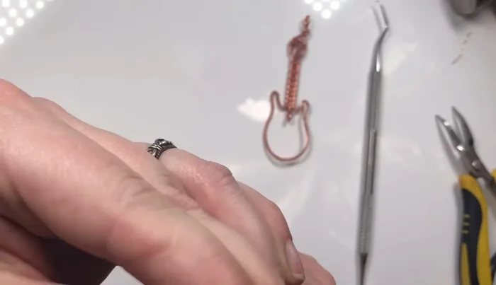 Create a small treble clef charm from a 2 1/2 inch piece of 16 gauge wire (or 18 gauge for easier manipulation). Ensure it fits within the guitar body.