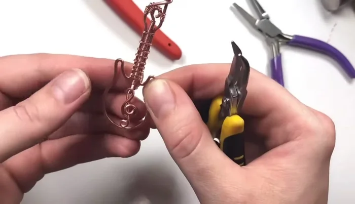 Hang the treble clef charm from the bottom loop of the eye pin, taking advantage of the perpendicular loop design for optimal placement.