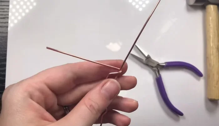 Close the frame by wrapping one side around the other and snipping off the excess wire. Create a loop at the top for the necklace bail.