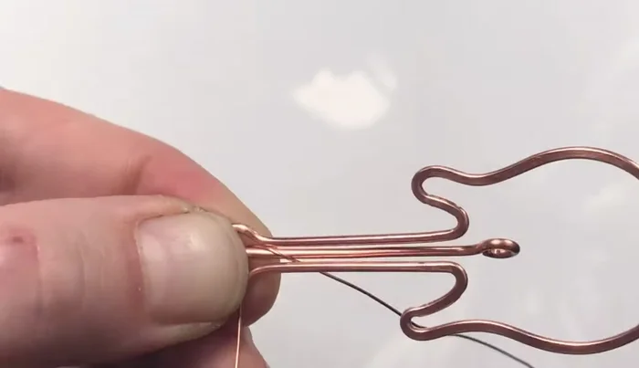 Coil the 26 gauge wire around the center wire to create frets, decreasing the number of coils per fret to mimic the spacing on a real guitar (start with 10 coils, then reduce for subsequent frets).