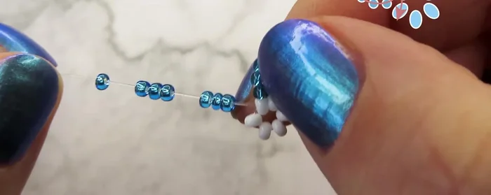 Add 7 beads and pull the cord through the two beads from the previous petal, then the white bead and the next one.