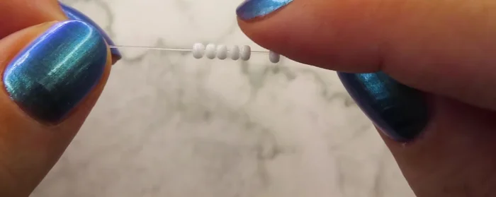 Add 7 beads and pull the cord through the two beads from the previous petal, then the white bead and the next one.