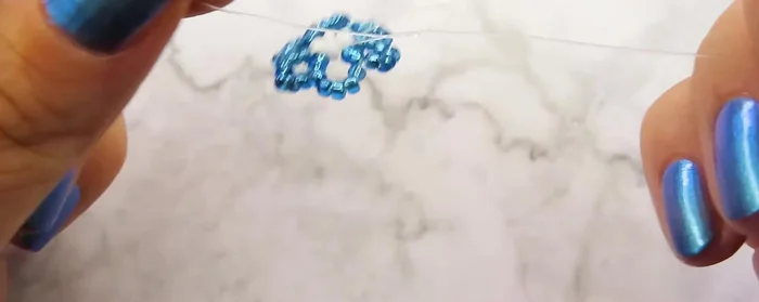 Tie two knots to secure the first flower.