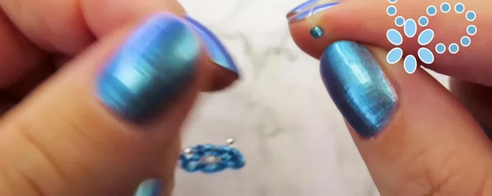 Thread the cord through the first blue bead closest to the flower, then through the previous flower's beads.