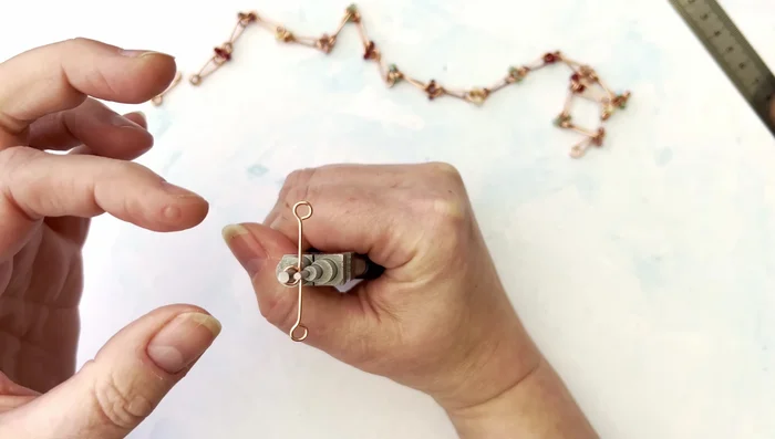 Flip the piece over. Bend the loops together again, this time with one loop going over the other.