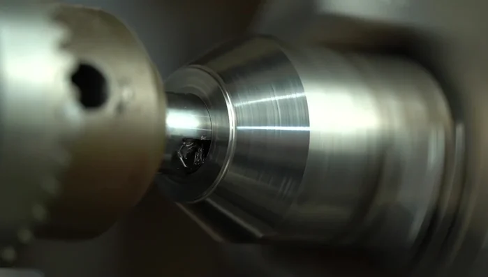 Refine the titanium ring edge on the lathe to ensure a proper fit with the koa wood.