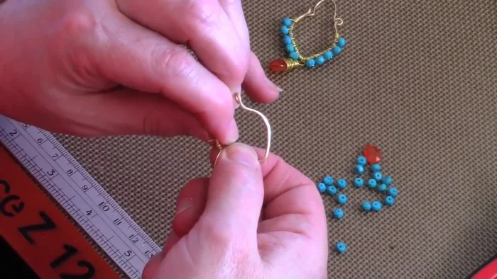 Attach the beading wire: Wrap the wire around one side of the frame once or twice, then wrap the tail around to secure; aim for around four wraps total. Use chain nose pliers to secure the wraps.