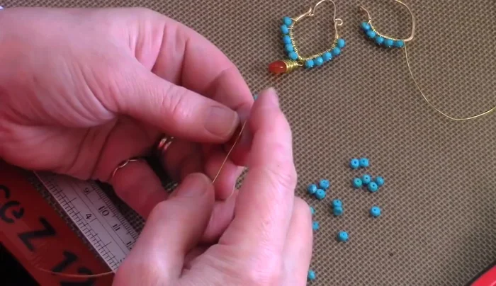 Add center briolette bead: String a carnelian briolette bead onto 24 gauge wire, bending the wires up to frame the top of the bead, and then creating a loop at the top.