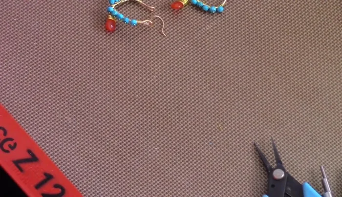 Attach ear wires: Cut 1.5 inches of 20 gauge wire. Create a loop on one end, bend it around a pen to shape it, and attach it to the frame loops. File the ends to remove any sharp edges.