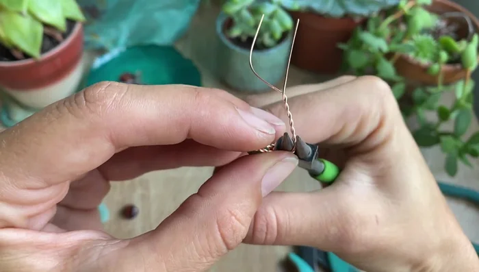 Use round nose pliers to curve the top wire to create a bell shape.