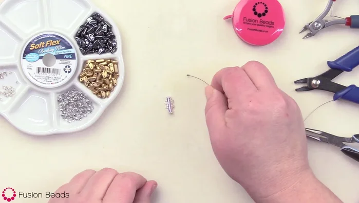 Cut 10 inches of beading wire. Attach one crimp bead to one loop of the 2-bar clasp, going through the loop and back through the crimp bead. Crimp securely using crimping pliers.