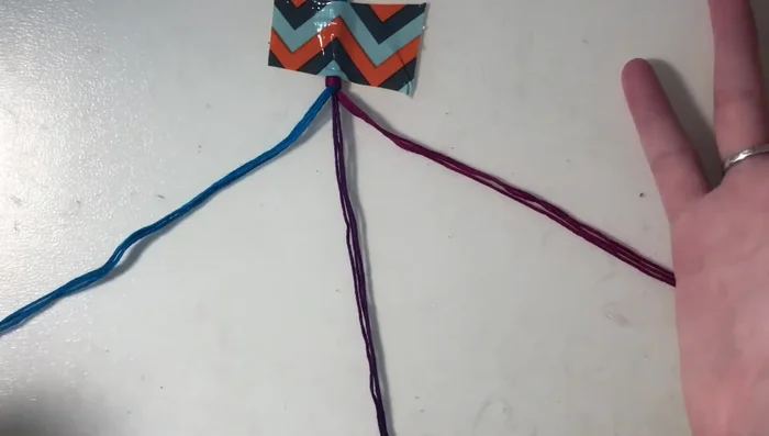 Return to the next outer string of the first color (blue). Create forward knots (as in step 4) on the remaining strings of this color and the other color group (purple), but not the string you just worked with.