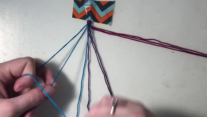 Return to the next outer string of the first color (blue). Create forward knots (as in step 4) on the remaining strings of this color and the other color group (purple), but not the string you just worked with.