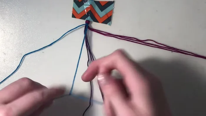 Return to the next outer string of the first color (blue). Create forward knots (as in step 4) on the remaining strings of this color and the other color group (purple), but not the string you just worked with.