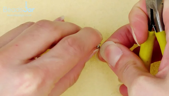 Close the clasp around the crimp beads using flat nose pliers.