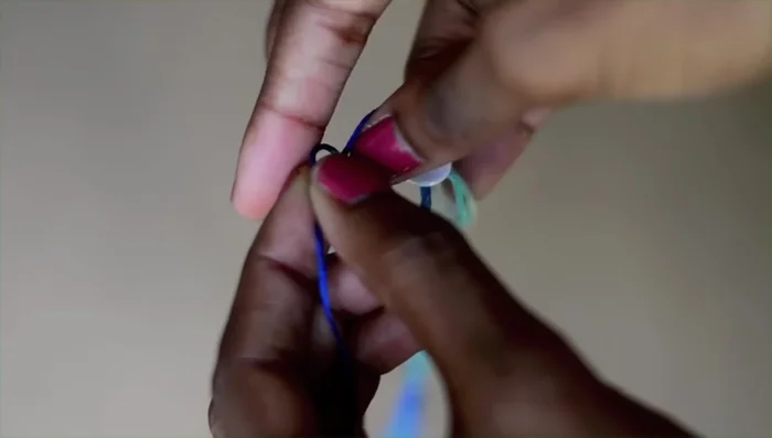 Attach the button: Add a button by picking any two strands, threading them through the holes of the button, and tying them to secure it. Cut off any excess thread.