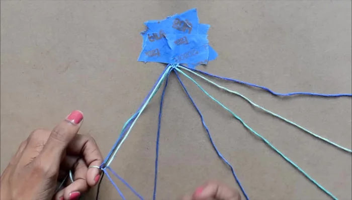 Create the chevron pattern: Starting with the leftmost strand, make a knot by forming a four over the second strand, pulling it under and through the hole, and tightening. Repeat once more. Repeat this process, moving from left to right, forming two knots over each strand until you reach the center.