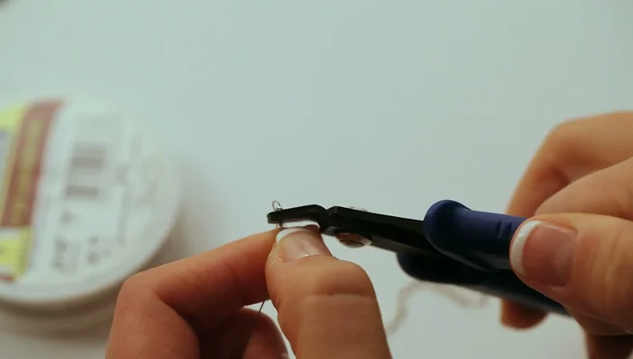 Turn the crimp tube 90° and fold it in half. Trim the wire and repeat on the other side.