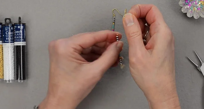 Attach the earring wire: Open the loop of the earring wire using chain nose pliers. Carefully thread the wire onto the top loop of the beaded eye pin, ensuring the leaf charm faces forward. Close the loop securely.