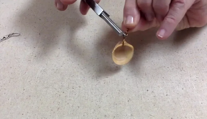 Wrap the wire around the loop, creating the bail. Wrap it multiple times for a more secure and organic look.