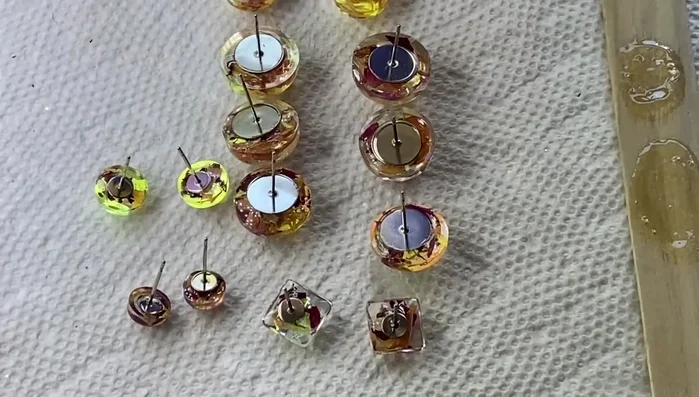 For the stud earrings, apply UV resin to the earring backs, attach to the pieces, and cure with UV light for 30 seconds to a minute. Add more resin to secure the back. Cure for 4-5 minutes.