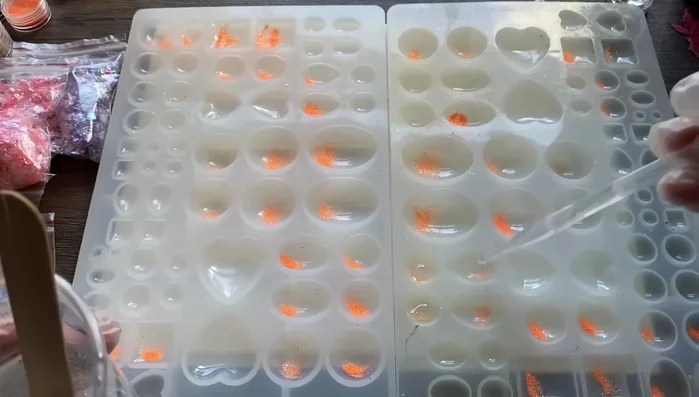 Pour a thin layer of resin into molds, mixing in the glitter.