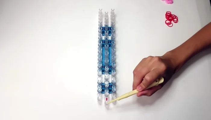 Prepare your loom: Ensure the three rows are offset, with the middle row closest to you and the pin openings facing away.