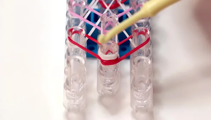 Finishing the loom: Continue hooking the white and colored bands until you reach the end of the loom. Hook the final triangle red band to the last pin on the middle row.