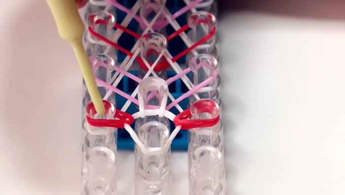Finishing the loom: Continue hooking the white and colored bands until you reach the end of the loom. Hook the final triangle red band to the last pin on the middle row.