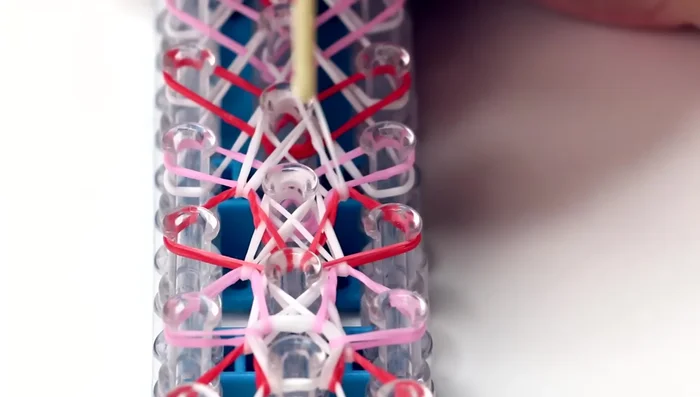 Finishing the loom: Continue hooking the white and colored bands until you reach the end of the loom. Hook the final triangle red band to the last pin on the middle row.