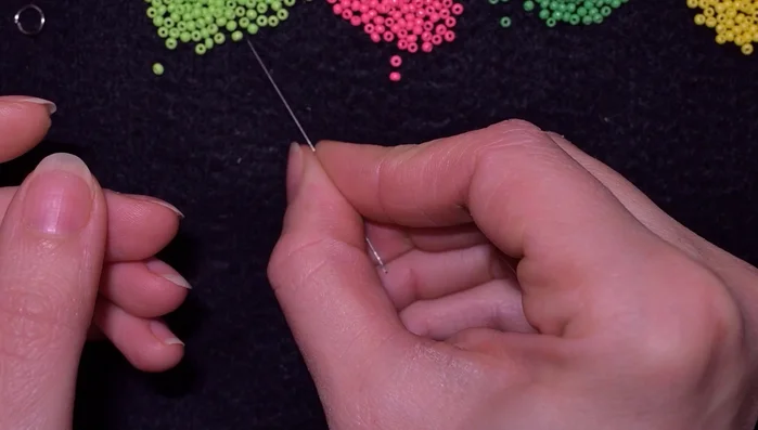 Pick up two green beads and two pink beads. Slide them down the needle. Make a knot by looping the thread twice and pulling tight.