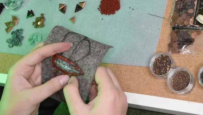 Add peacock feathers to the bottom wings, securing them with small stitches.