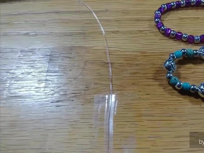 Secure the cord: Tape one end of the stretchy cord to a surface to prevent beads from rolling away.