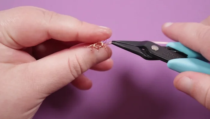 Secure the spikes by twisting the ends for sturdiness. Add the Rosemonte in the center by weaving the remaining copper wire through the holes and wrapping around the base circles.