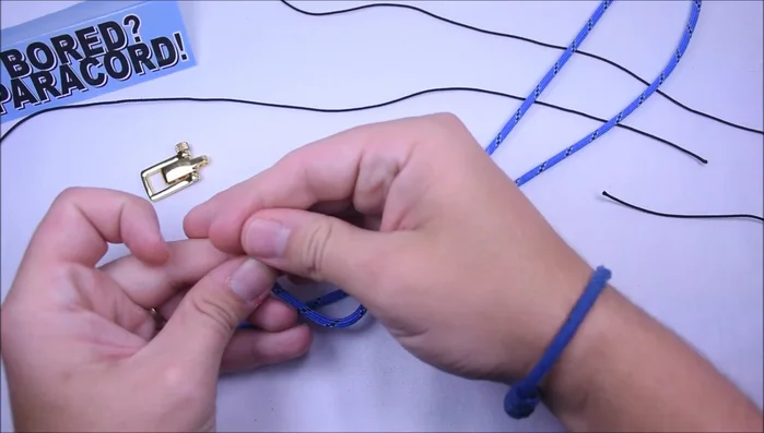 Attach the mini shackle: Insert both ends of the paracord through the mini shackle, making sure it's on its smallest setting. Pull it tight to secure it.