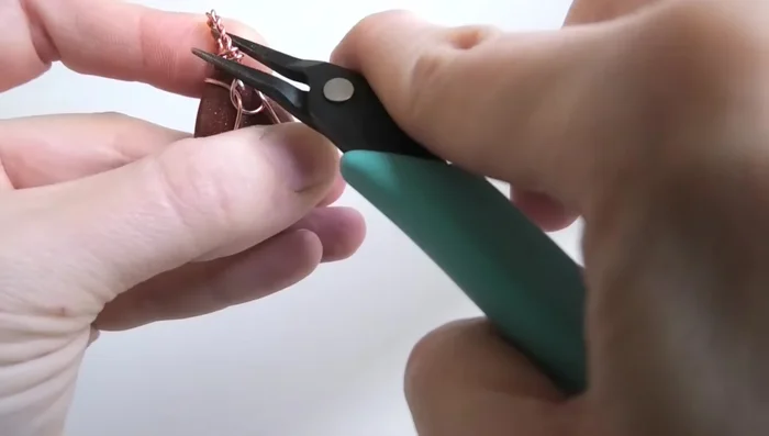 Tighten the wires around the bail using pliers, ensuring symmetry.