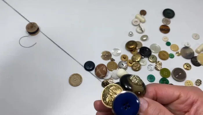 To create a “button shaft” for dangling elements, sew the button in place, leaving some space, and wrap the thread several times around the elastic before securing it. 